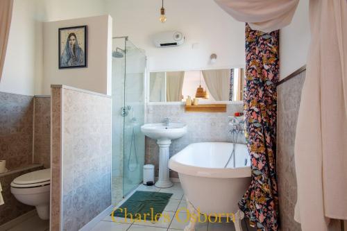 a bathroom with a tub and a toilet and a sink at Maison de l'Octroi - terrasse, jardin, vue Etang in Sète