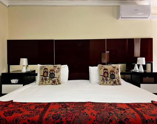 um quarto com uma cama grande com lençóis brancos e almofadas em Keeme-Nao Hotel em Mahalapye