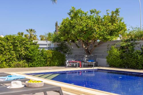 プロタラスにあるAzure Luxury Pool Villaのテーブルと木が植えられた庭のスイミングプール