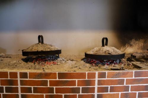 twee ijzeren pannen bovenop een stenen open haard bij Restorant Ballkoni Beratit in Berat