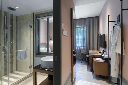 a bathroom with a sink and a shower and a desk at The Jesselton Hotel in Kota Kinabalu