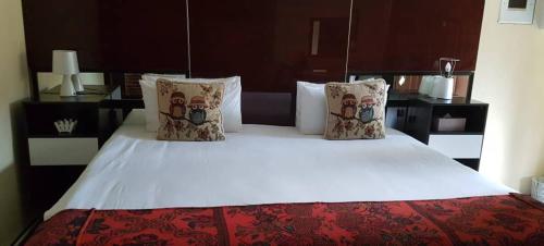 um quarto com uma grande cama branca com almofadas em Keeme-Nao Hotel em Mahalapye