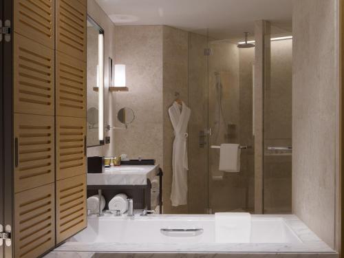 a bathroom with a tub and a shower with a sink at Le Méridien Xiaojing Bay in Huizhou