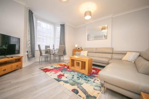 a living room with a couch and a tv and a table at Beautiful Ground Floor Victorian Apartment in Clacton-on-Sea