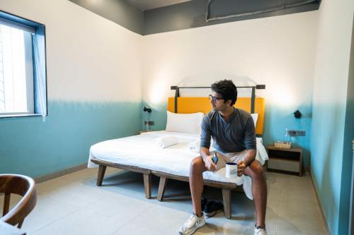 um homem sentado numa cama num quarto em Draper Startup House for Entrepreneurs Hyderabad em Hyderabad