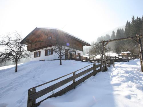 a cabin in the snow with a fence at Charming Holiday Home in H ttau with Barbecue in Hüttau