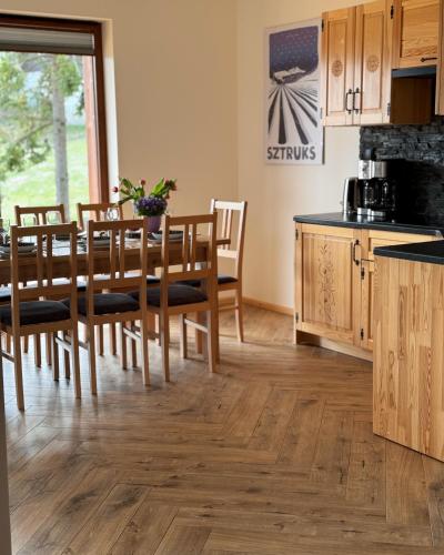 a kitchen with wooden floors and a table and chairs at Apartamenty na Soszowie, Wisła - widokowe miejsce z Balią & Prywatną Sauną, obok stoku narciarskiego i Bike Parku, dla max 16 osób in Wisła