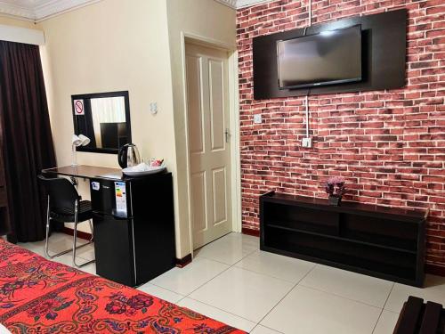 um quarto com uma parede de tijolos e uma televisão na parede em Keeme-Nao Hotel em Mahalapye