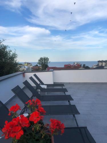 a group of chairs sitting on a roof with red flowers at Hotel Tadora in Eforie Nord