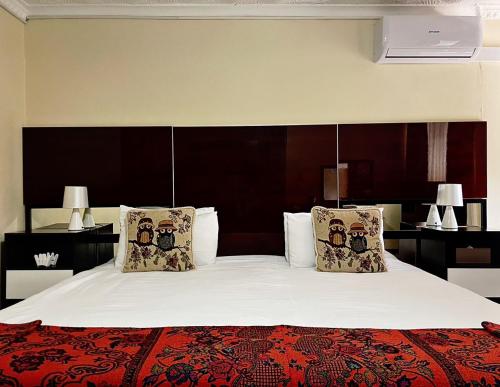 a bedroom with a large bed with white sheets and pillows at Keeme-Nao Hotel in Mahalapye