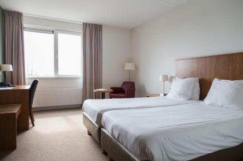 a hotel room with a large bed and a desk at Strandhotel Vigilante in Makkum