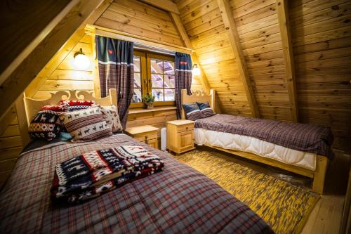 a bedroom with two beds in a log cabin at Azyl nad Nidą in Rębów