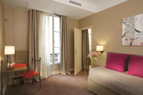 a bedroom with a bed and a window with pink pillows at Hôtel Londres et New York - Teritoria in Paris
