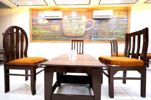 a wooden table with two chairs and a sign on a wall at The Crown Hotel in Tājganj