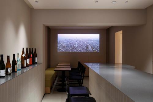 HotelCO Kuramae ホテル コ 蔵前 في طوكيو: بار به زجاجات من النبيذ وطاولة