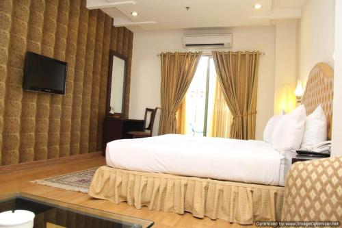 Un dormitorio con una gran cama blanca y una ventana en Hotel Javson, en Sialkot