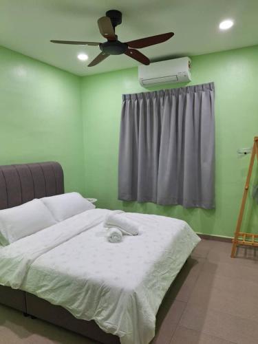 a bedroom with a bed with a ceiling fan at K.Cottage in Muar