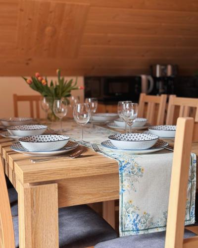 a wooden table with plates and wine glasses on it at Apartamenty na Soszowie, Wisła - widokowe miejsce z Balią & Prywatną Sauną, obok stoku narciarskiego i Bike Parku, dla max 16 osób in Wisła