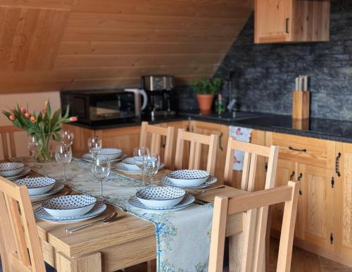 a table with plates and wine glasses on it in a kitchen at Apartamenty na Soszowie, Wisła - widokowe miejsce z Balią & Prywatną Sauną, obok stoku narciarskiego i Bike Parku, dla max 16 osób in Wisła