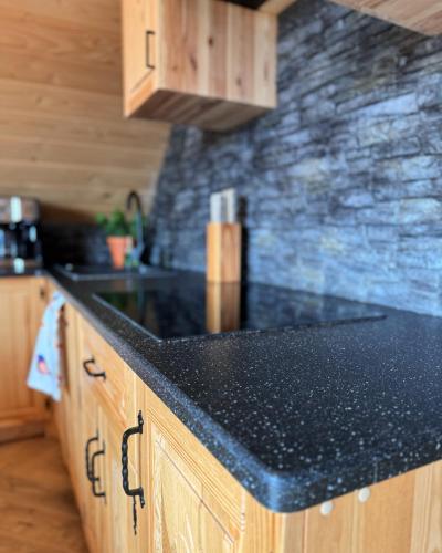 a kitchen with a black counter top and wooden cabinets at Apartamenty na Soszowie, Wisła - widokowe miejsce z Balią & Prywatną Sauną, obok stoku narciarskiego i Bike Parku, dla max 16 osób in Wisła