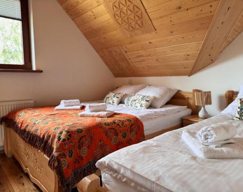 a bedroom with two beds and a wooden ceiling at Apartamenty na Soszowie, Wisła - widokowe miejsce z Balią & Prywatną Sauną, obok stoku narciarskiego i Bike Parku in Wisła