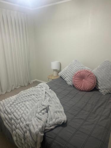 Dormitorio con cama con almohada rosa en Raceway Getaway, en New Plymouth