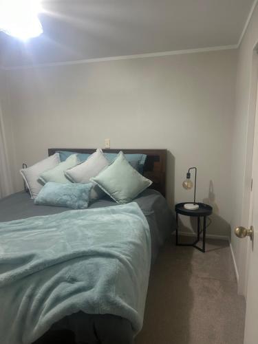 1 dormitorio con 1 cama grande con almohadas blancas en Raceway Getaway, en New Plymouth