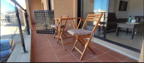 Duas cadeiras de madeira e uma mesa numa varanda em Apartamento Saul em Beniarbeig