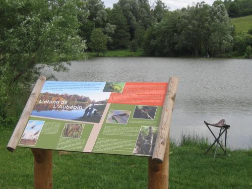 a sign in the grass next to a lake at Chez Odette et Ricardo Meximieux - Pérouges in Meximieux
