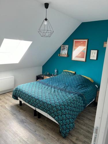 - une chambre dotée d'un lit avec un mur bleu dans l'établissement Maison pour 4 personnes proche Caen et mer, à Saint-Manvieu