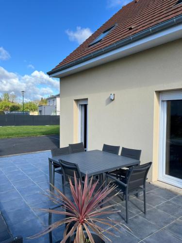 - une table et des chaises noires sur la terrasse dans l'établissement Maison pour 4 personnes proche Caen et mer, à Saint-Manvieu