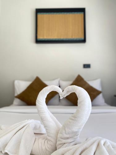 two towel swans making a heart on a bed at Flora Hostel KhaoSok in Khao Sok