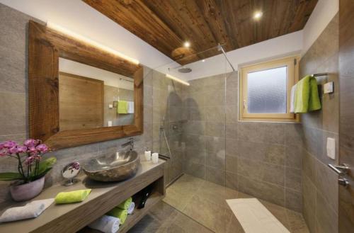 ein Bad mit einem Waschbecken und einem Spiegel in der Unterkunft Chalet Resort Innerluferhof in Riffian