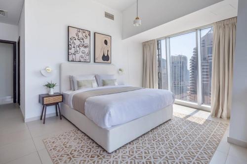 a white bedroom with a large bed and a large window at Frank Porter - Cayan Tower in Dubai