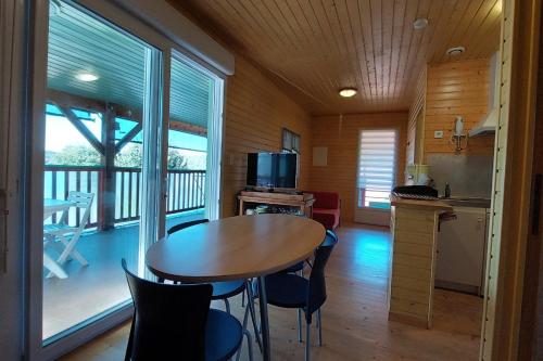 a dining room with a table and a kitchen with a balcony at maison en bois in Lacapelle-Viescamp