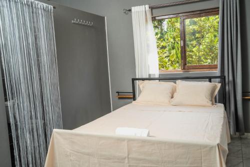 Schlafzimmer mit einem weißen Bett und einem Fenster in der Unterkunft Come IN Hôtel in Imerintsiatosika