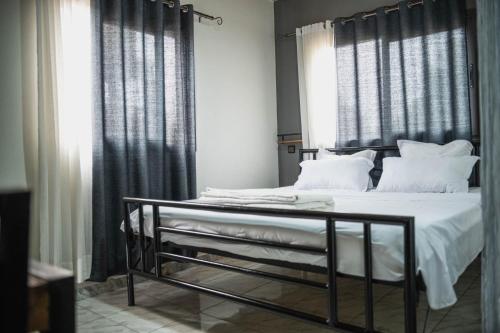 Come IN Hôtel في Imerintsiatosika: غرفة نوم بسرير ذو شراشف ووسائد بيضاء