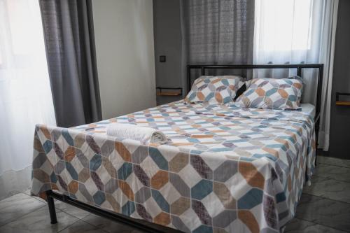 ein Bett mit einer Decke in einem Schlafzimmer in der Unterkunft Come IN Hôtel in Imerintsiatosika