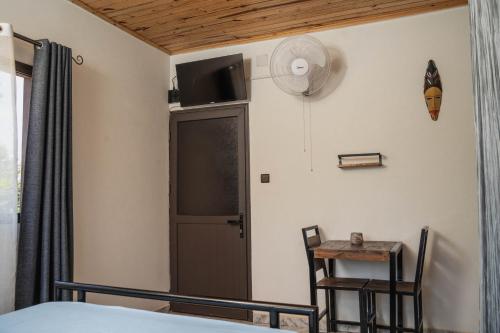 1 dormitorio con 1 cama, escritorio y ventilador en Come IN Hôtel, en Imerintsiatosika