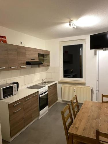 een keuken met houten kasten en een tafel met een tafel bij Monteurwohnung mit 5 Einzelbetten in Bitterfeld in Große Mühle