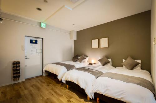 two beds in a room with a wall at Family Inn Nara in Nara