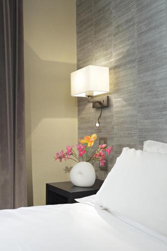 a bedroom with a bed and a vase with flowers on a table at Hôtel Londres et New York - Teritoria in Paris