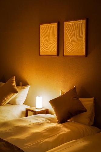 two beds in a room with a lamp on a table at Family Inn Nara in Nara