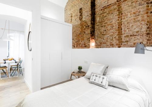 マドリードにあるConde de Peñalver Loftの白いベッドとレンガの壁が備わるベッドルーム1室が備わります。