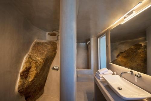 un bagno con lavandino e una grande roccia sul muro di Villa Sun Sky a Aggelika