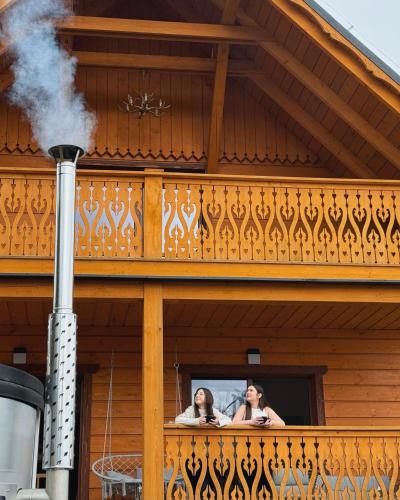 two women looking out of a balcony with smoke coming out at Apartamenty na Soszowie, Wisła - widokowe miejsce z Balią & Prywatną Sauną, obok stoku narciarskiego i Bike Parku, dla max 16 osób in Wisła
