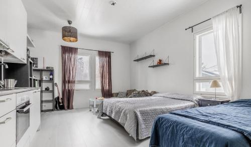 a white bedroom with two beds and a kitchen at Cozy apartment in Espoo