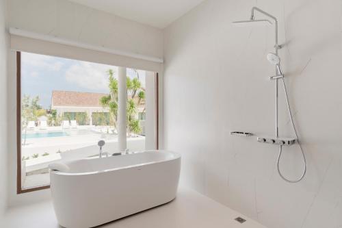 a white bathroom with a tub and a window at Emmarin Villa Pattaya in Nong Prue