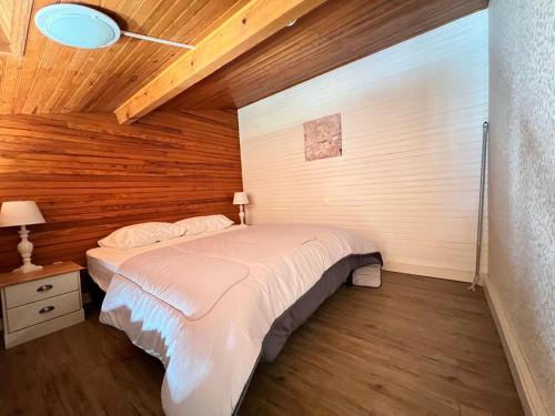 ein Schlafzimmer mit einem Bett und einer Holzwand in der Unterkunft Studette et studio en montagne proche stations de ski et lac in Prunières
