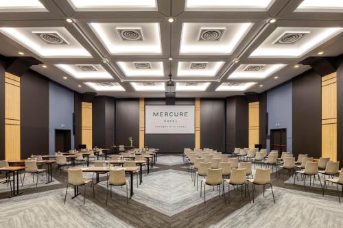 a conference room with tables and chairs and a screen at Mercure Antwerp City South in Antwerp
